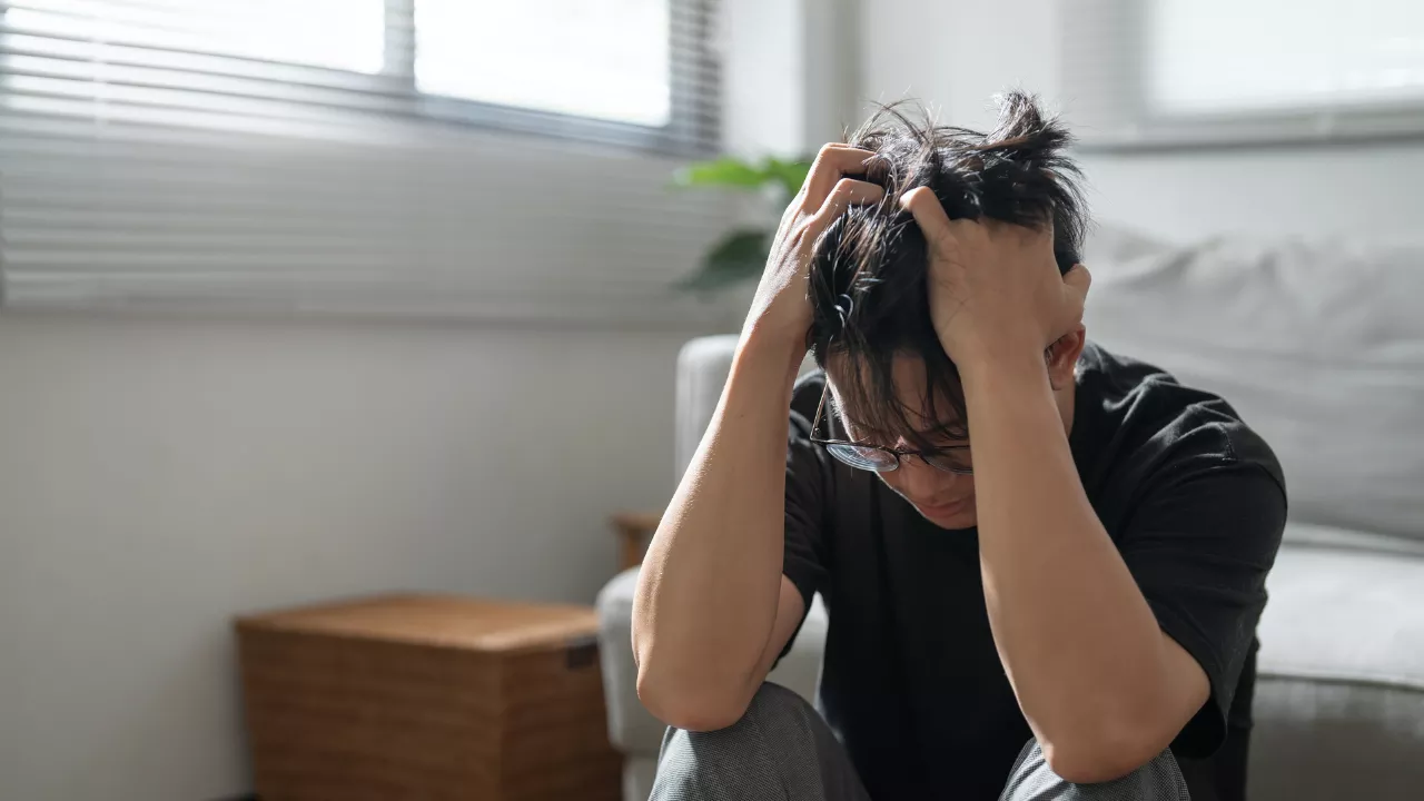 Person sitting and holding their head in distress — representing anxiety-related dizziness, PPPD, or functional dizziness associated with anxiety disorders