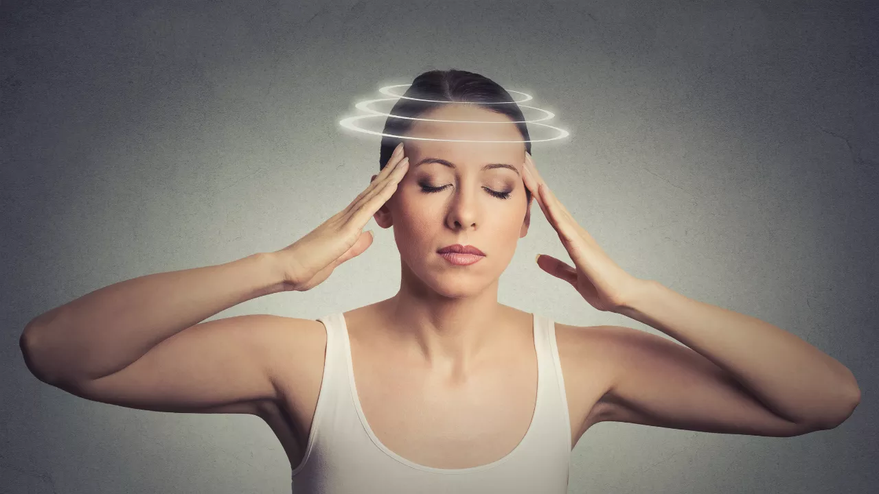 Woman holding her head with chronic vertigo or persistent dizziness — representing PPPD or chronic vestibular syndrome