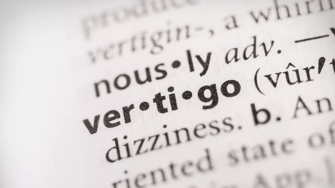 Dictionary page with the word 'vertigo' in focus — defining vertigo as a sensation of spinning or dizziness