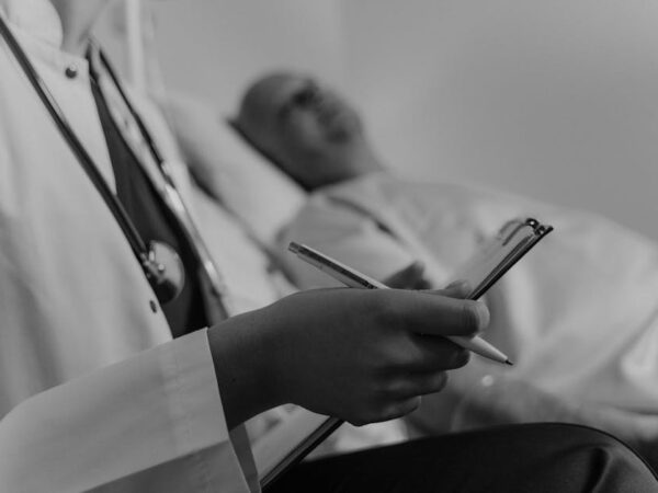 Doctor with stethoscope taking notes by patient in bed — बैंगलोर मैनुवर | Dr. Prateek Porwal, ENT