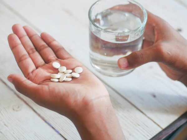 Hand holding pills and glass of water for medication — चक्कर में खान-पान | Dr. Prateek Porwal, ENT