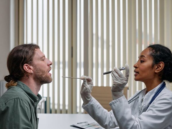 Doctor examines patient's throat with tongue depressor and light — चक्कर येण्याची ७ प्रमुख कारणे | Dr. Prateek Porwal, ENT