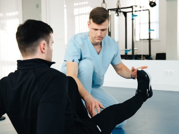 Doctor assisting patient with leg exercise in a clinic — Vertigo Doctor in Meerut | Dr. Prateek Porwal, ENT