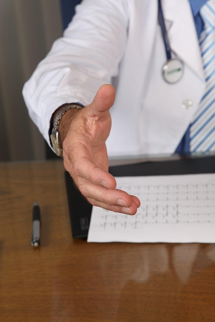 Doctor in white coat offering a handshake across a desk — Vertigo Doctor in Varanasi | Dr. Prateek Porwal, ENT