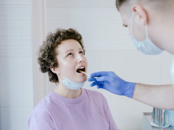 Doctor examining patient's throat with a tongue depressor — वेस्टिबुलर माइग्रेन क्या है | Dr. Prateek Porwal, ENT